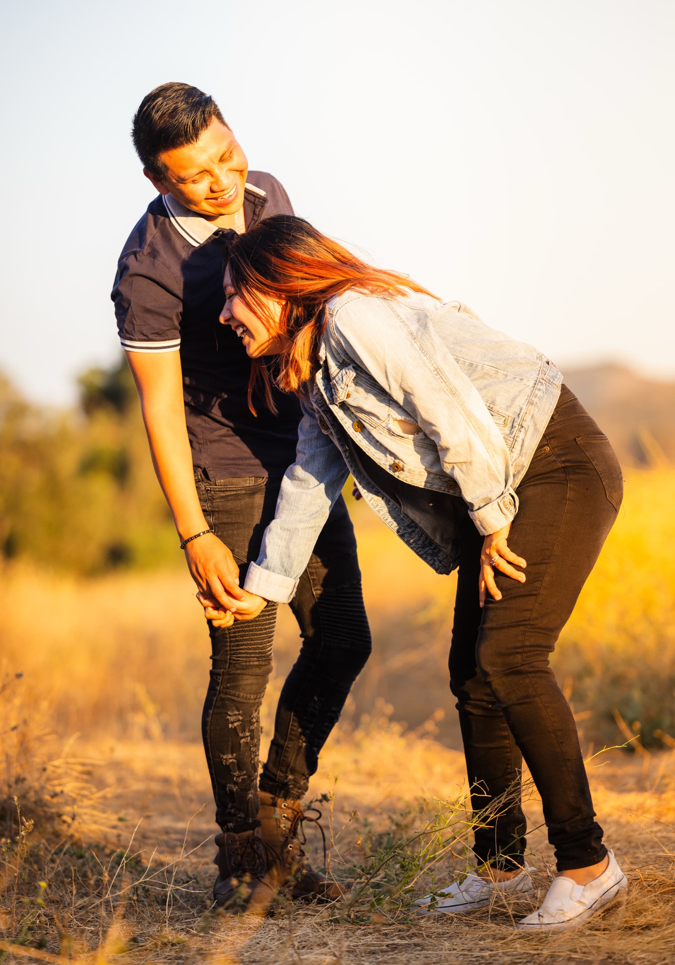 Couple cracking up mid-walk through golden grass