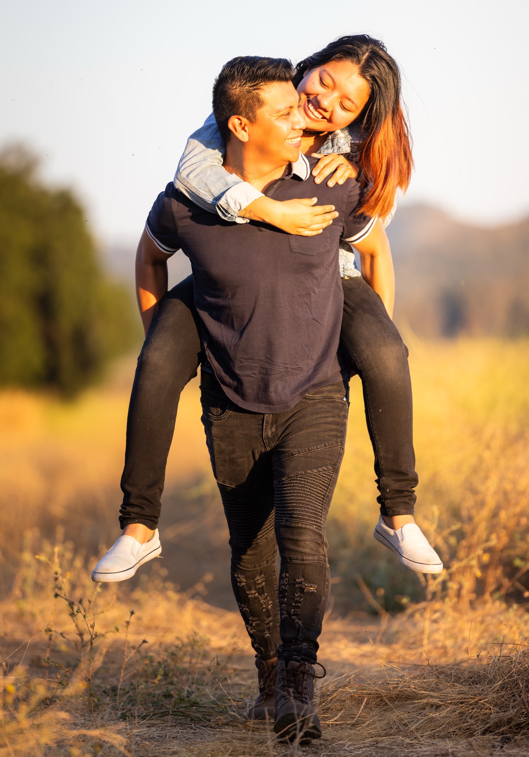 Piggyback through a golden field at sunset