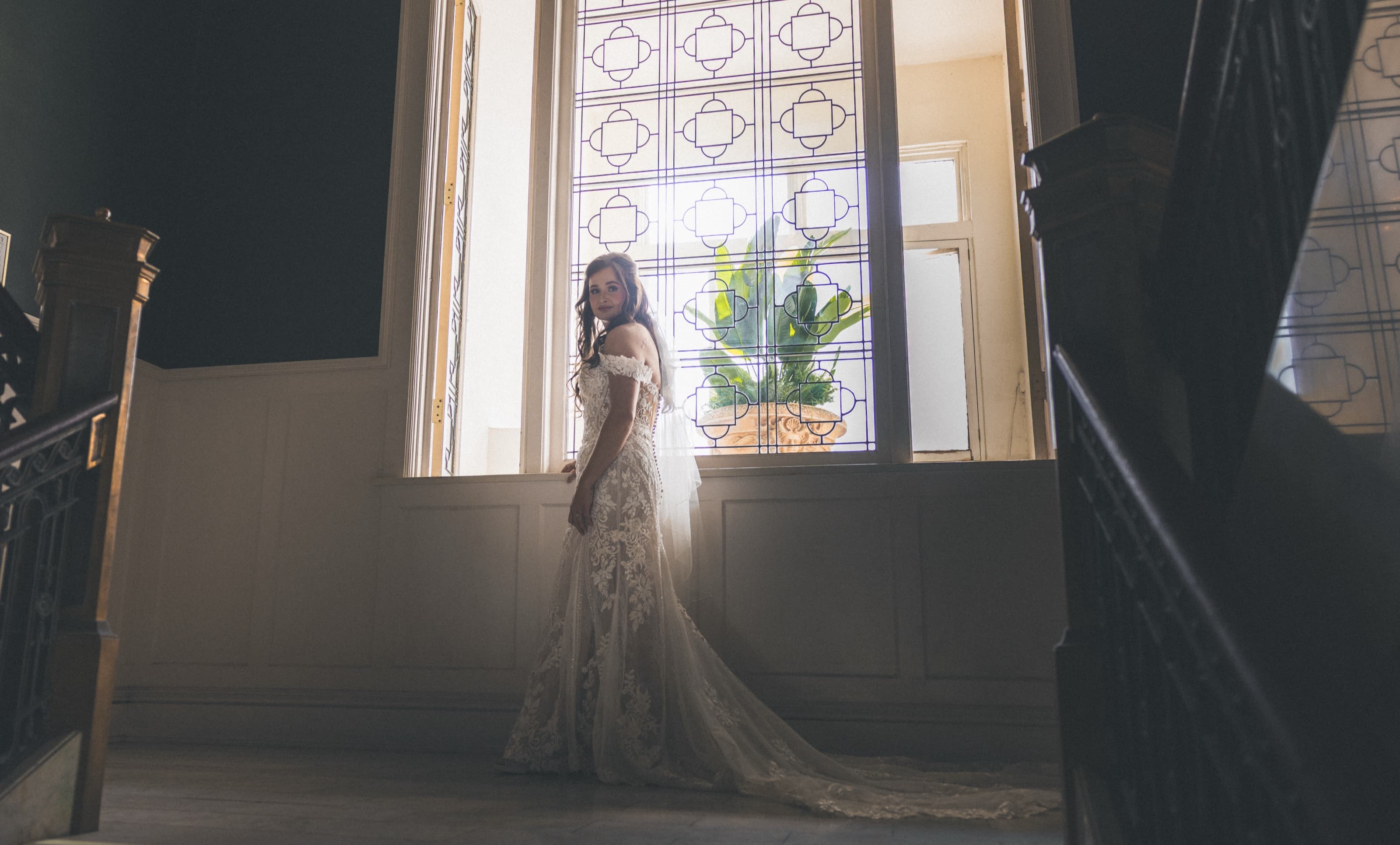 Bride in a lace gown in front of a tall stained-glass window