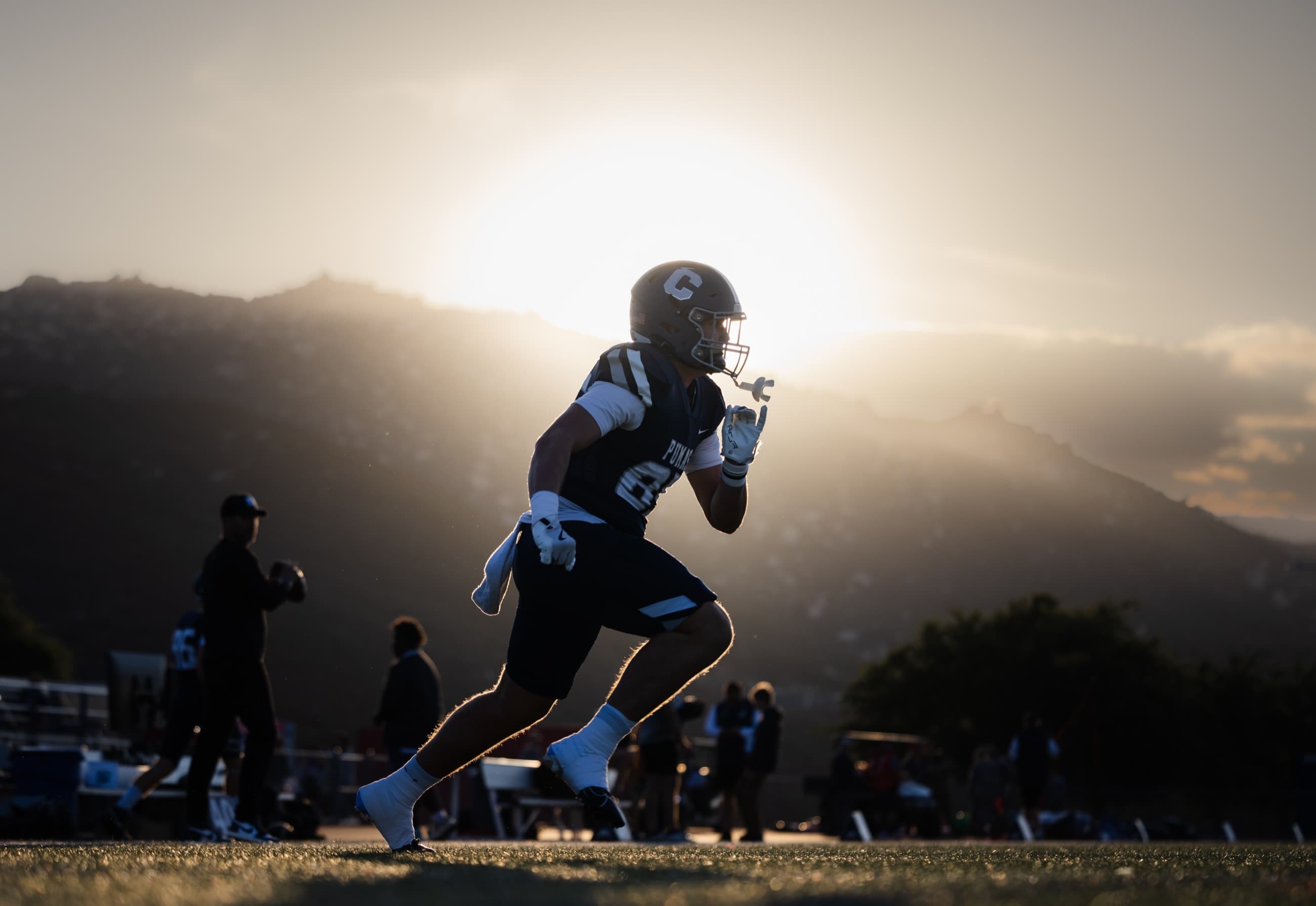 Athlete sprinting through warmups as the sun drops behind the hills